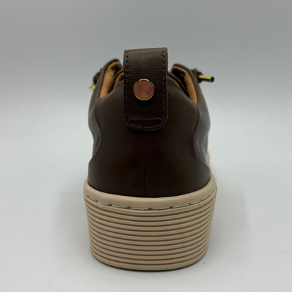 A close-up rear view of a brown leather shoe with a chunky beige platform sole and a small metallic pull tab on the heel.