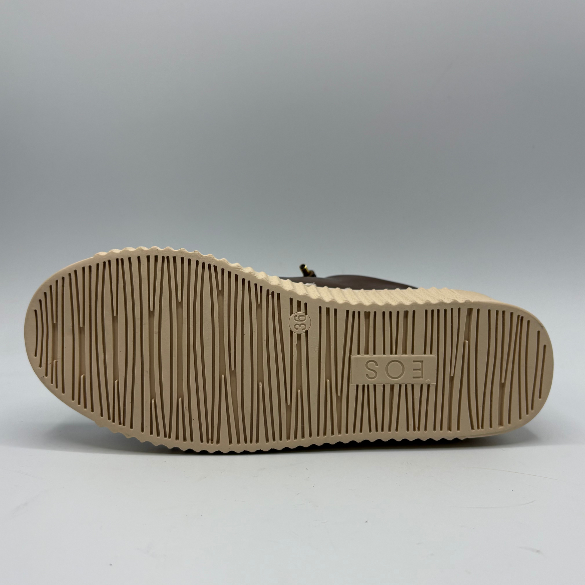 The outsole of a brown shoe, showing a beige tread pattern and a rubberized 'EOS' logo on the heel, photographed against a neutral gray background.