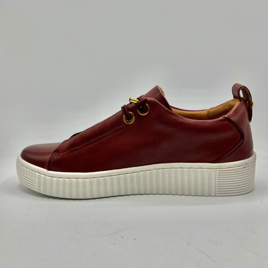 Brown leather sneaker with white sole on a gray background