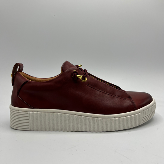 Brown leather sneaker with white sole on a gray background