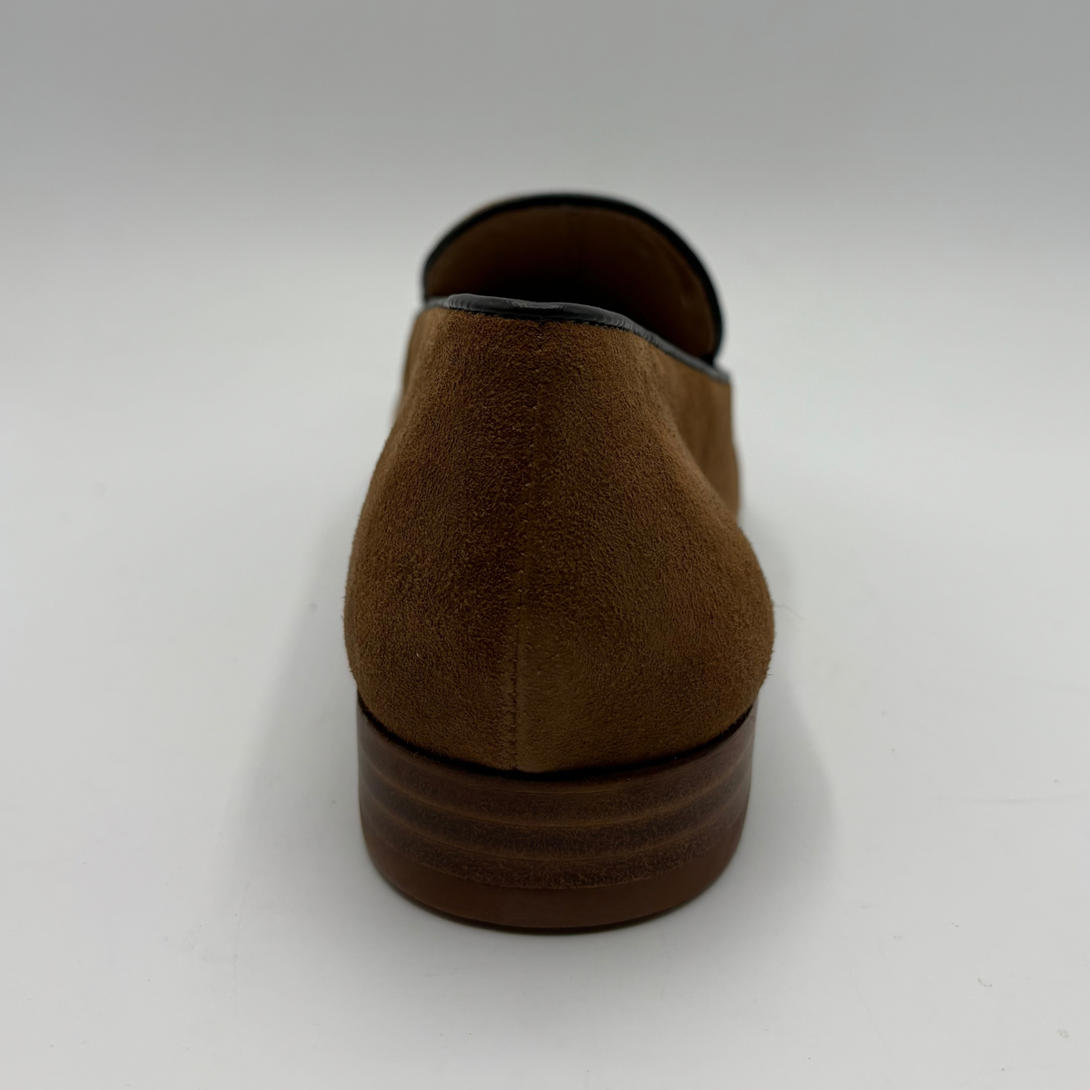 Back view of a brown leather loafer with a short stacked heel on a white background