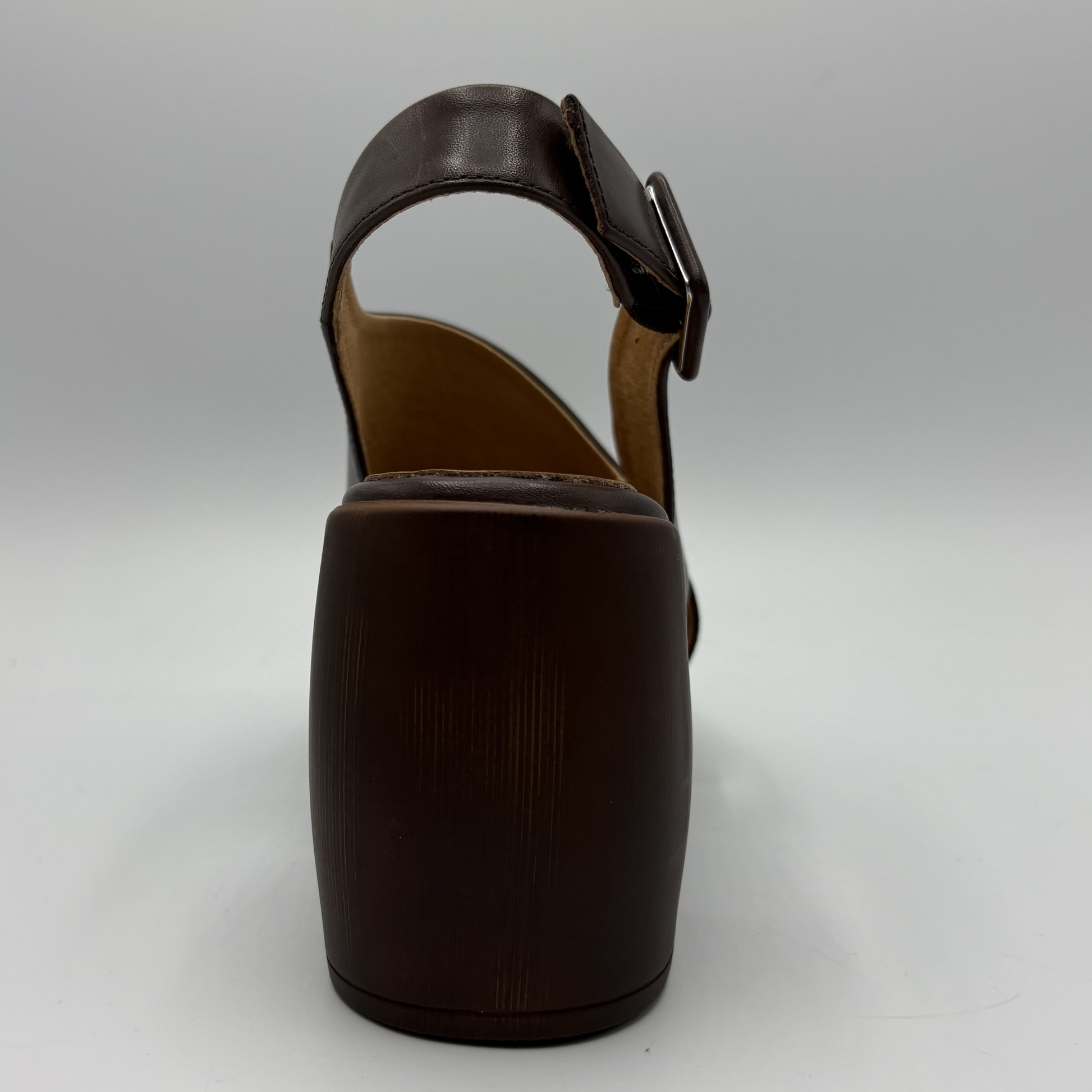 Brown sandal with a buckle on a light gray background