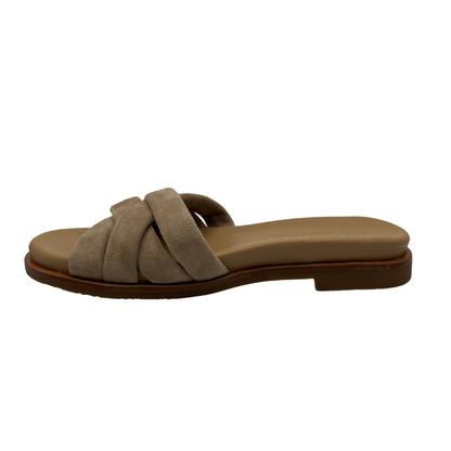 Left facing view of taupe suede slip on sandal with padded upper and footbed. Cross strap design and low heel.