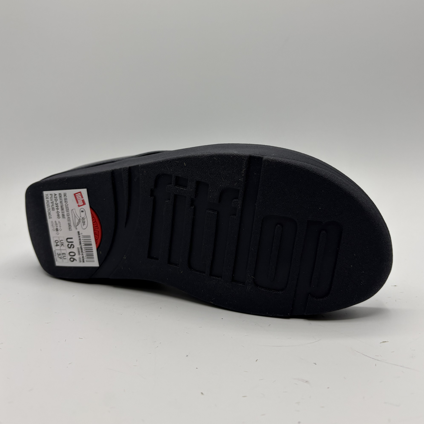 Black shoe sole with brand logo on a gray background