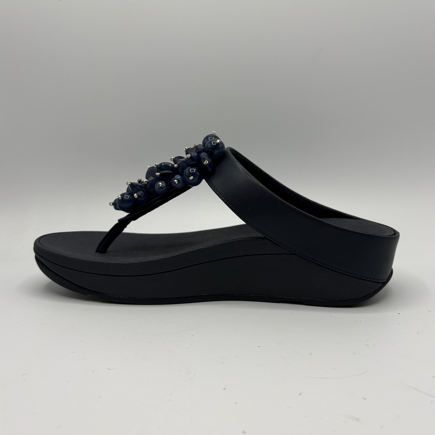 Navy sandal with decorative elements on a gray background