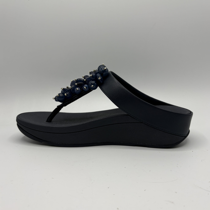 Navy sandal with decorative elements on a gray background