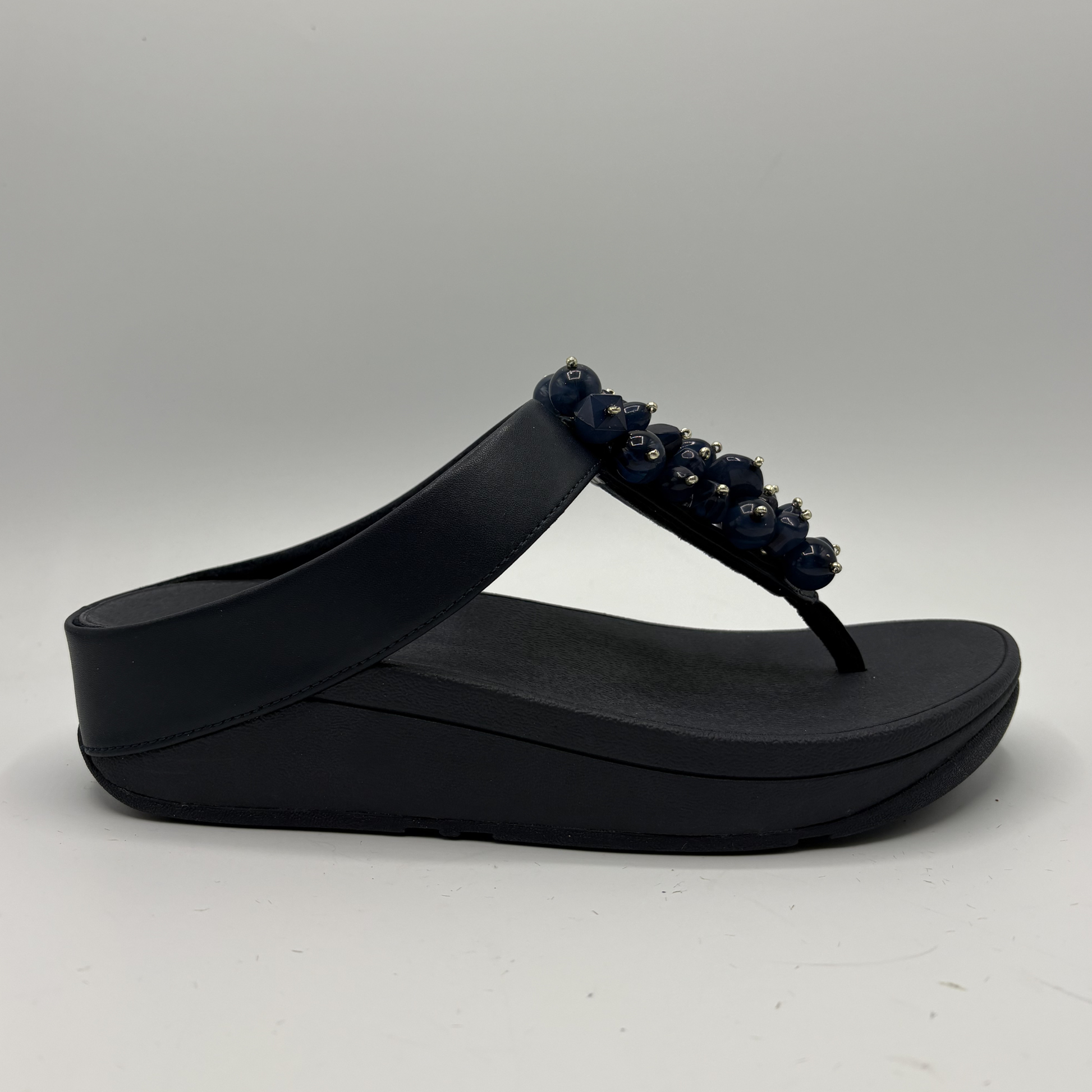 Navy sandal with decorative straps on a gray background