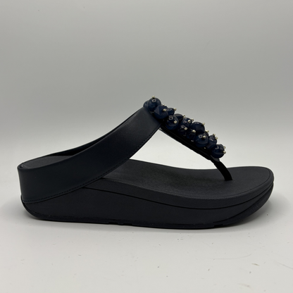 Navy sandal with decorative straps on a gray background