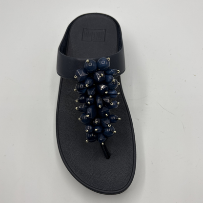 Black sandal with decorative elements on a gray background