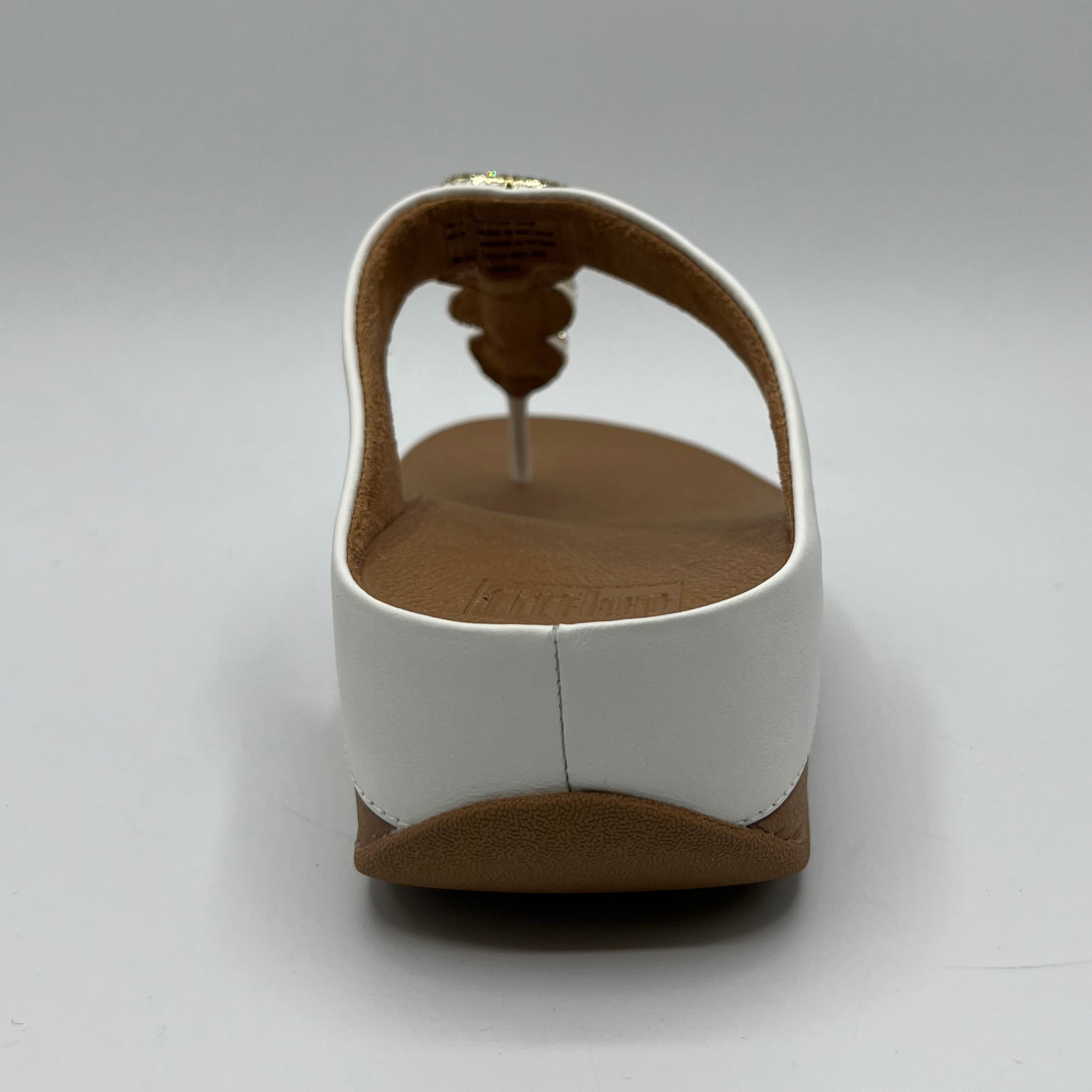 Back view of a leather wedge sandal with a white strap and toe post. Featuring a crystal chain detail on the strap.