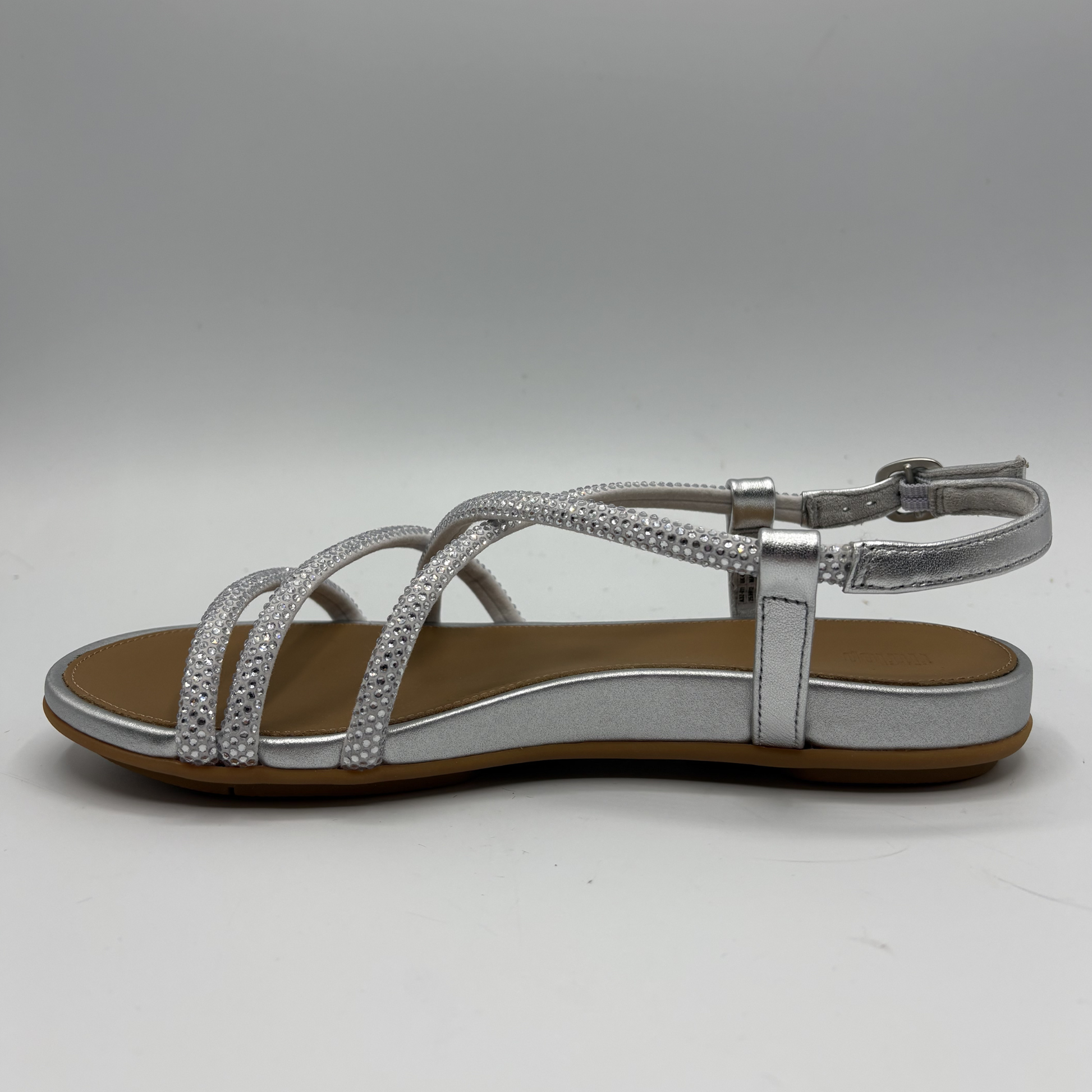 Silver sandal with brown sole on a gray background