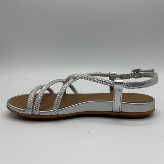 Silver sandal with brown sole on a gray background