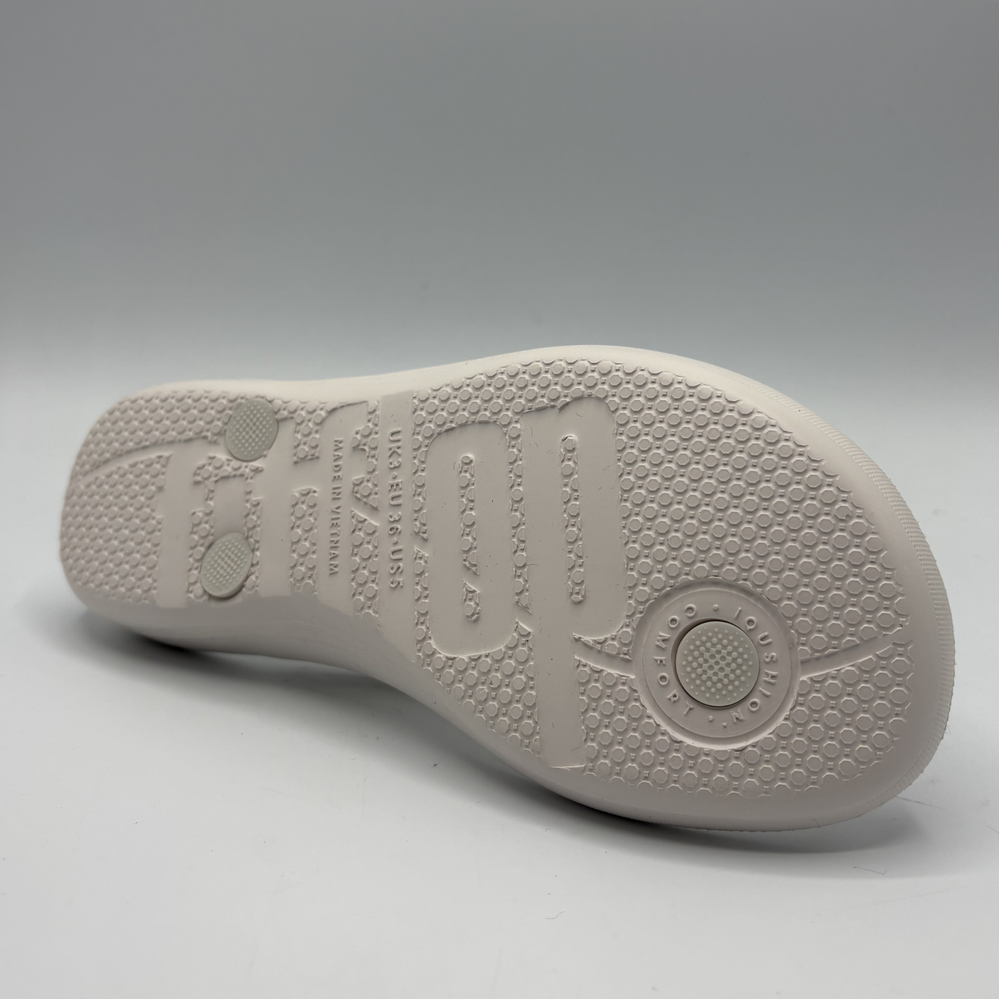 White shoe sole with brand logo on a gray background