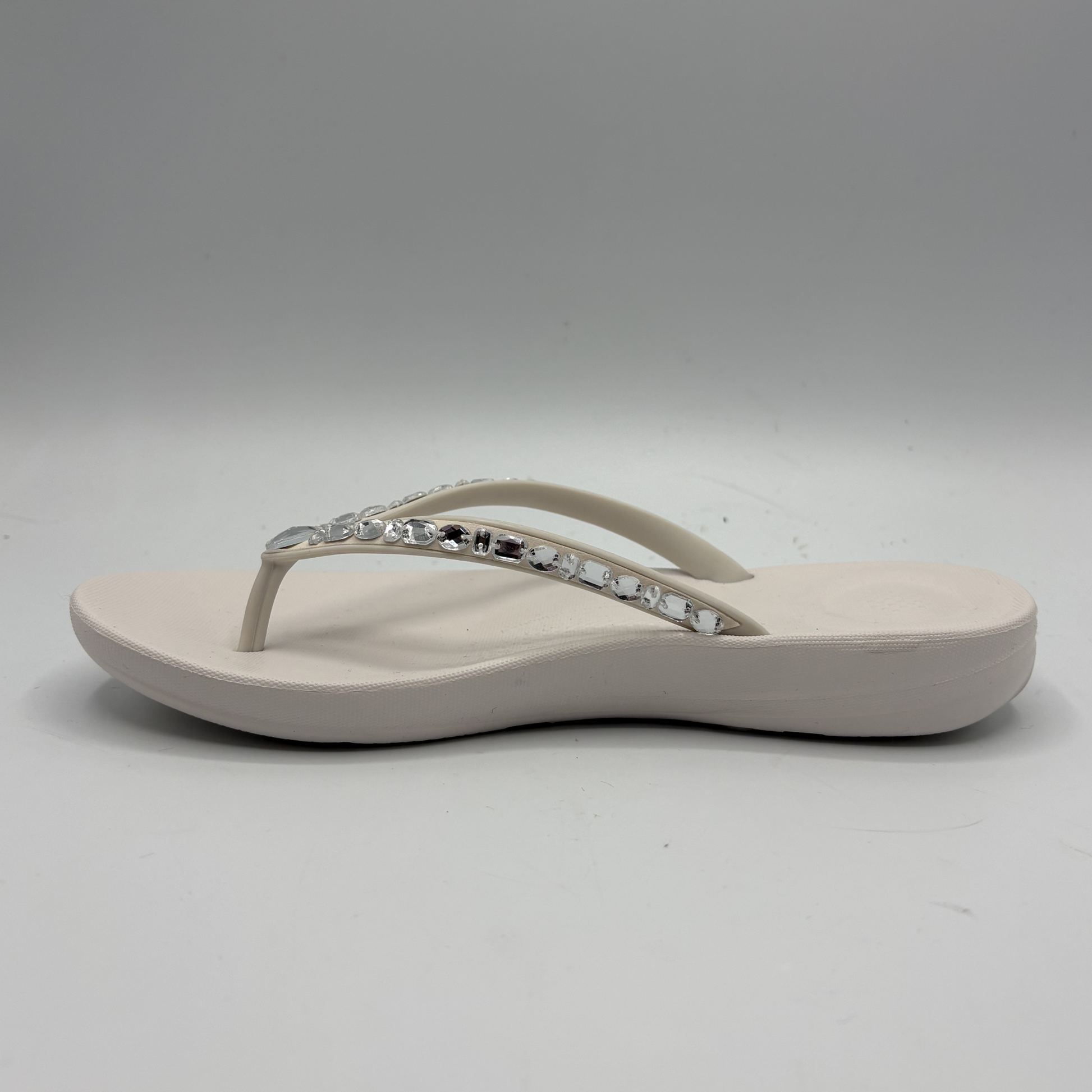 Beige sandal with a decorative strap on a gray background