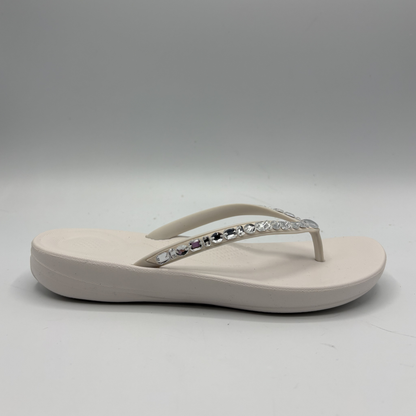 Beige sandal with decorative straps on a gray background