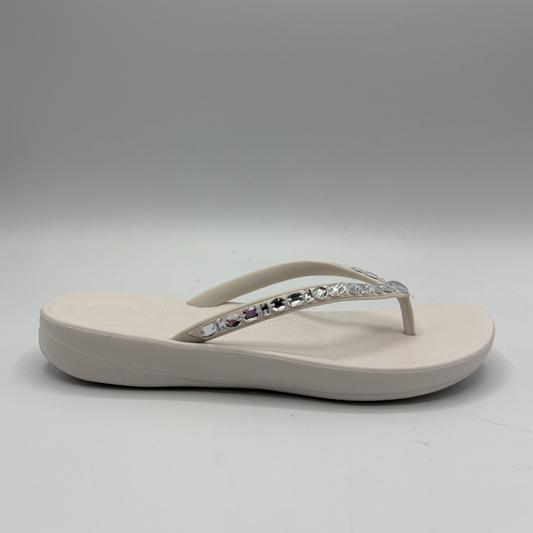 Beige sandal with decorative straps on a gray background