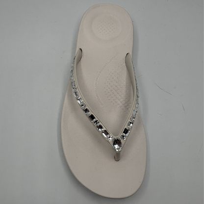 White flip-flop with decorative crystals on a gray background