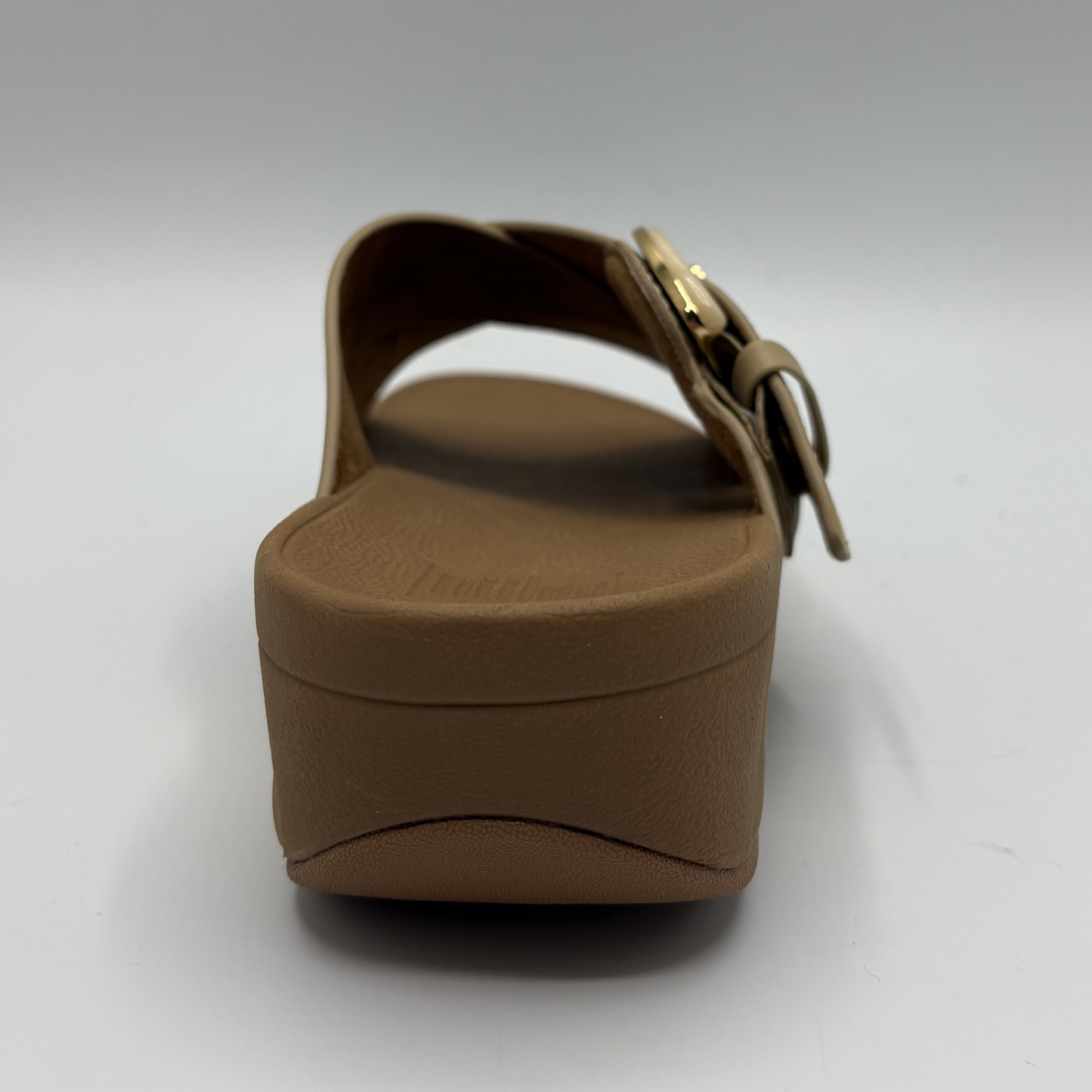 Brown sandal with a gold buckle on a white background