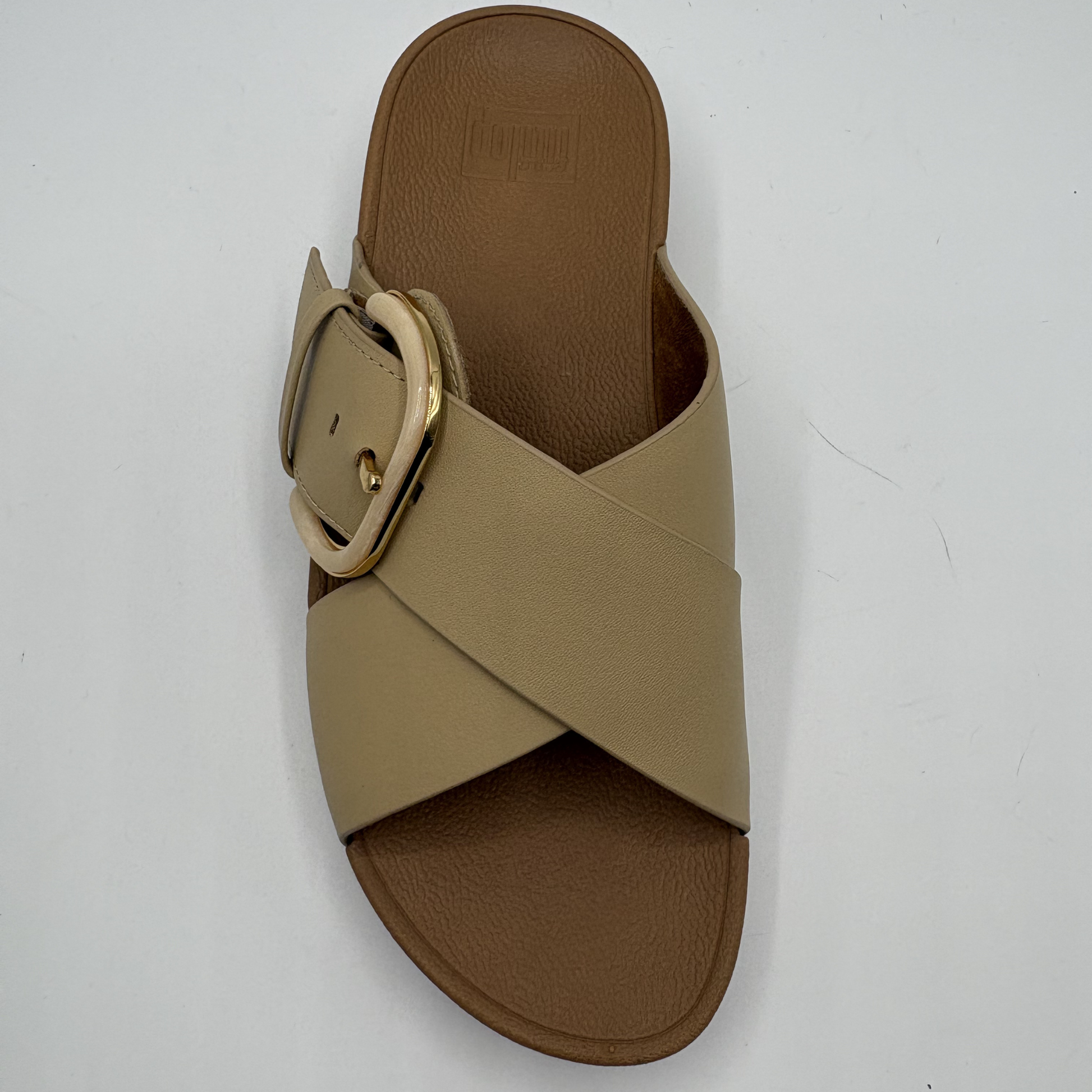 Beige sandal with a gold buckle on a white background