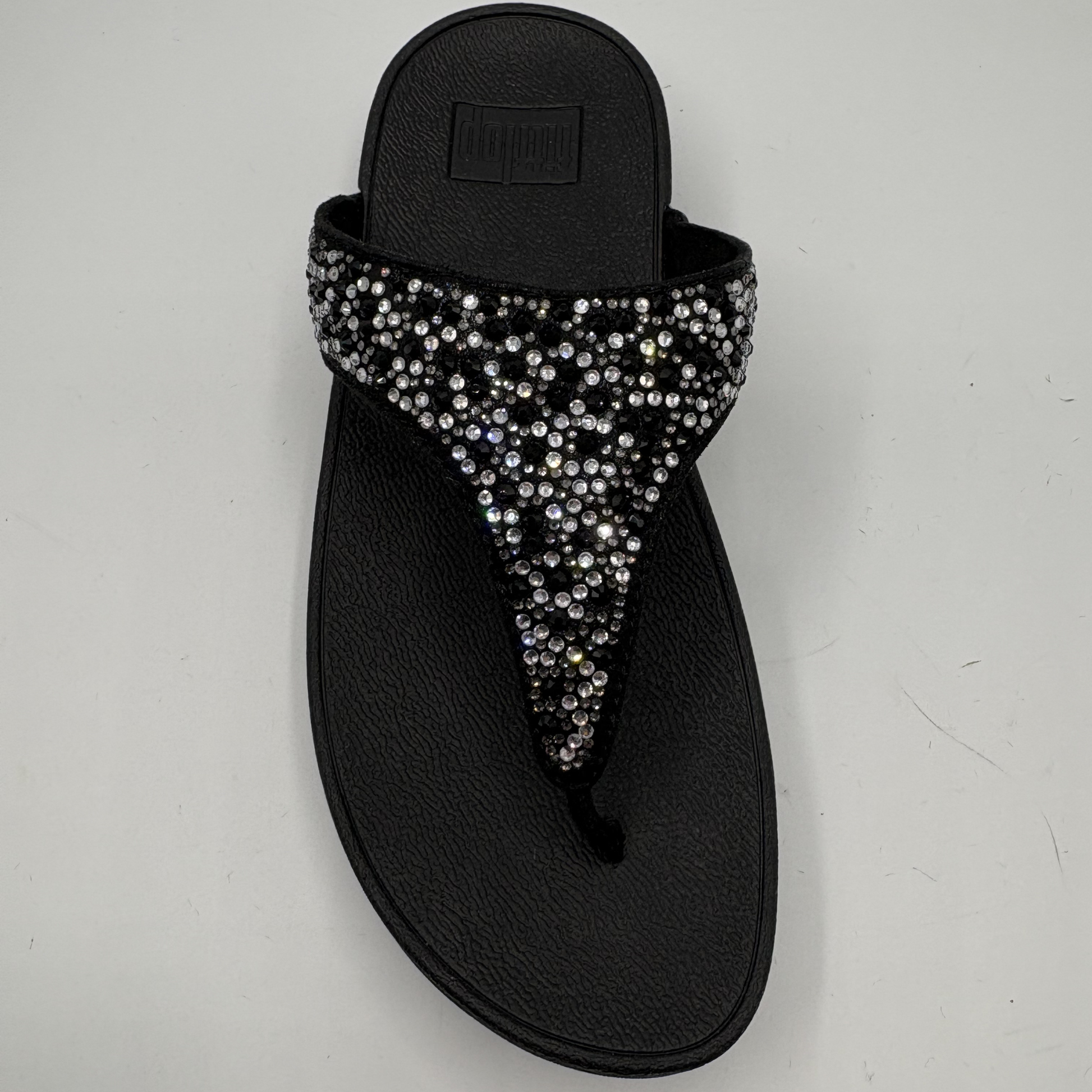 Black sandal with rhinestone embellishments on a light gray background