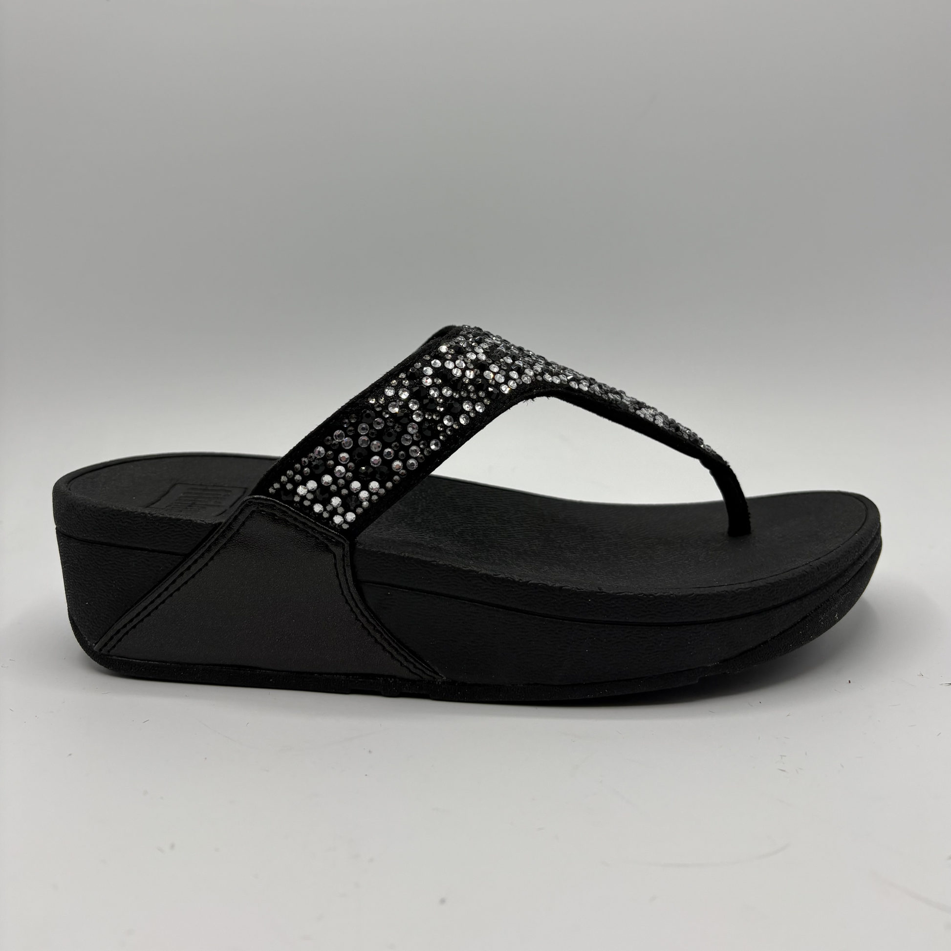 Black sandal with rhinestone embellishments on a gray background