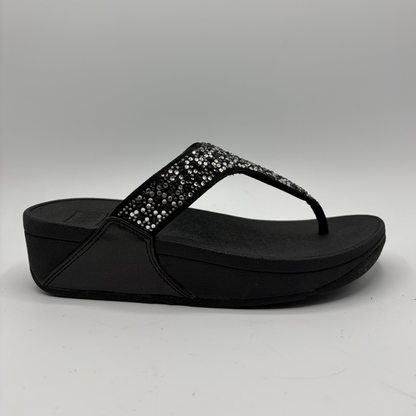 Black sandal with rhinestone embellishments on a gray background