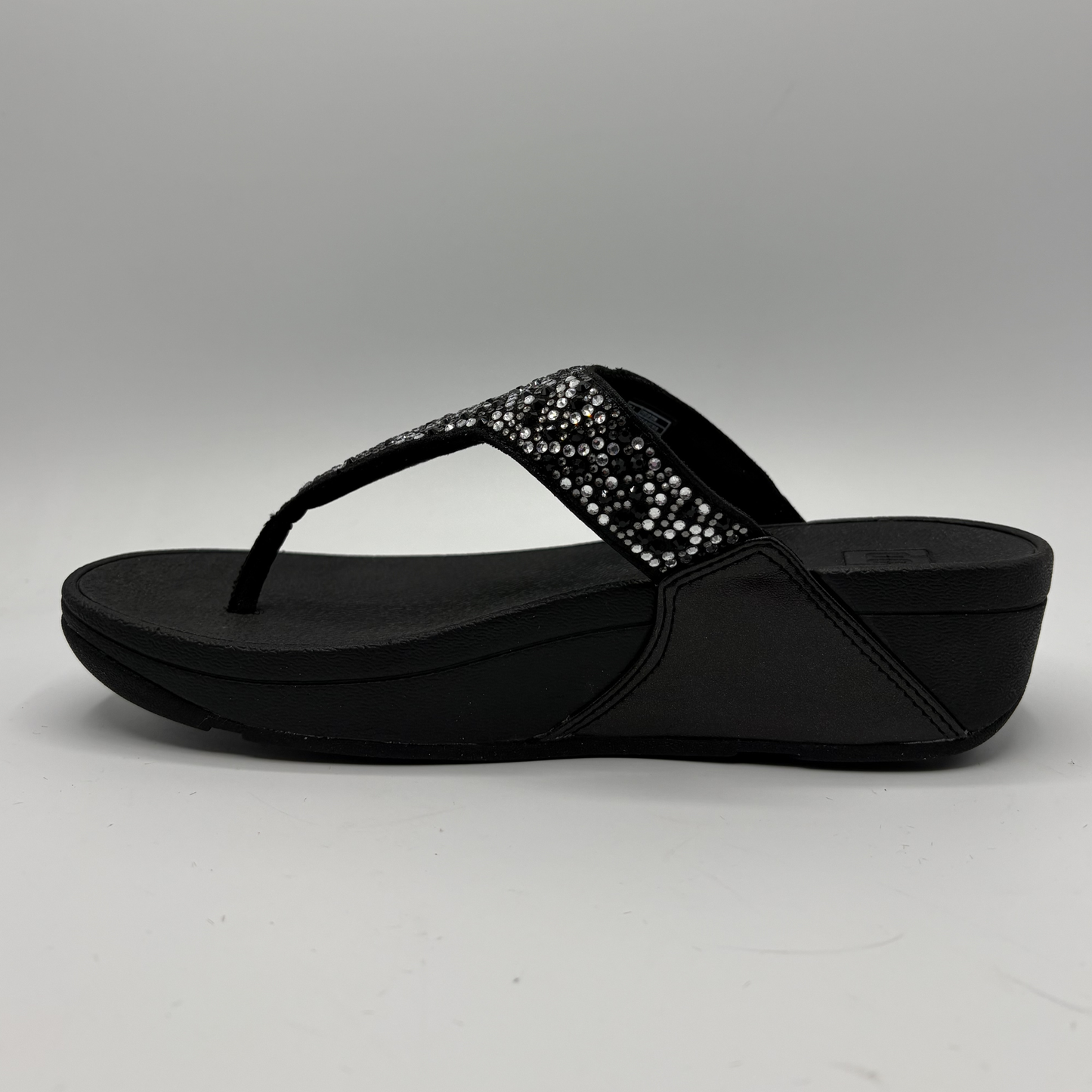 Black sandal with a decorative strap on a gray background