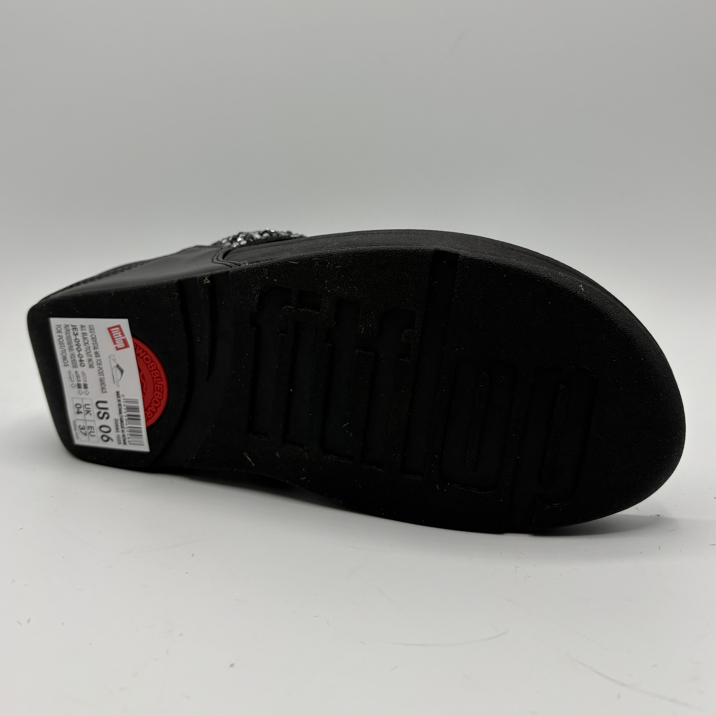 Black sandal with a visible brand label on a gray background