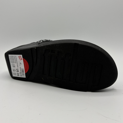 Black sandal with a visible brand label on a gray background