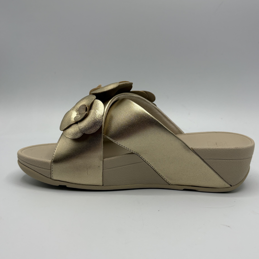 Beige sandal with a decorative flower on a gray background