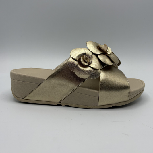Gold sandal with a decorative flower on a gray background