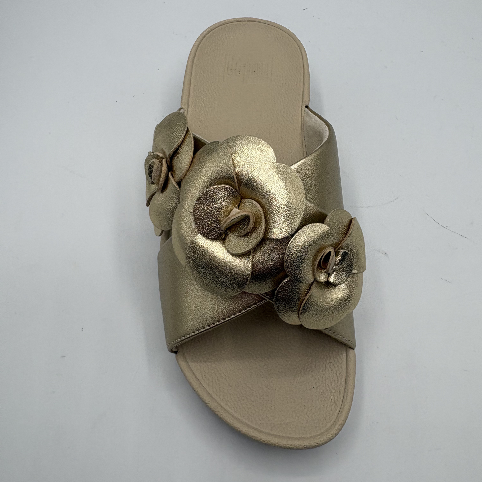 Gold sandal with floral designs on a white background