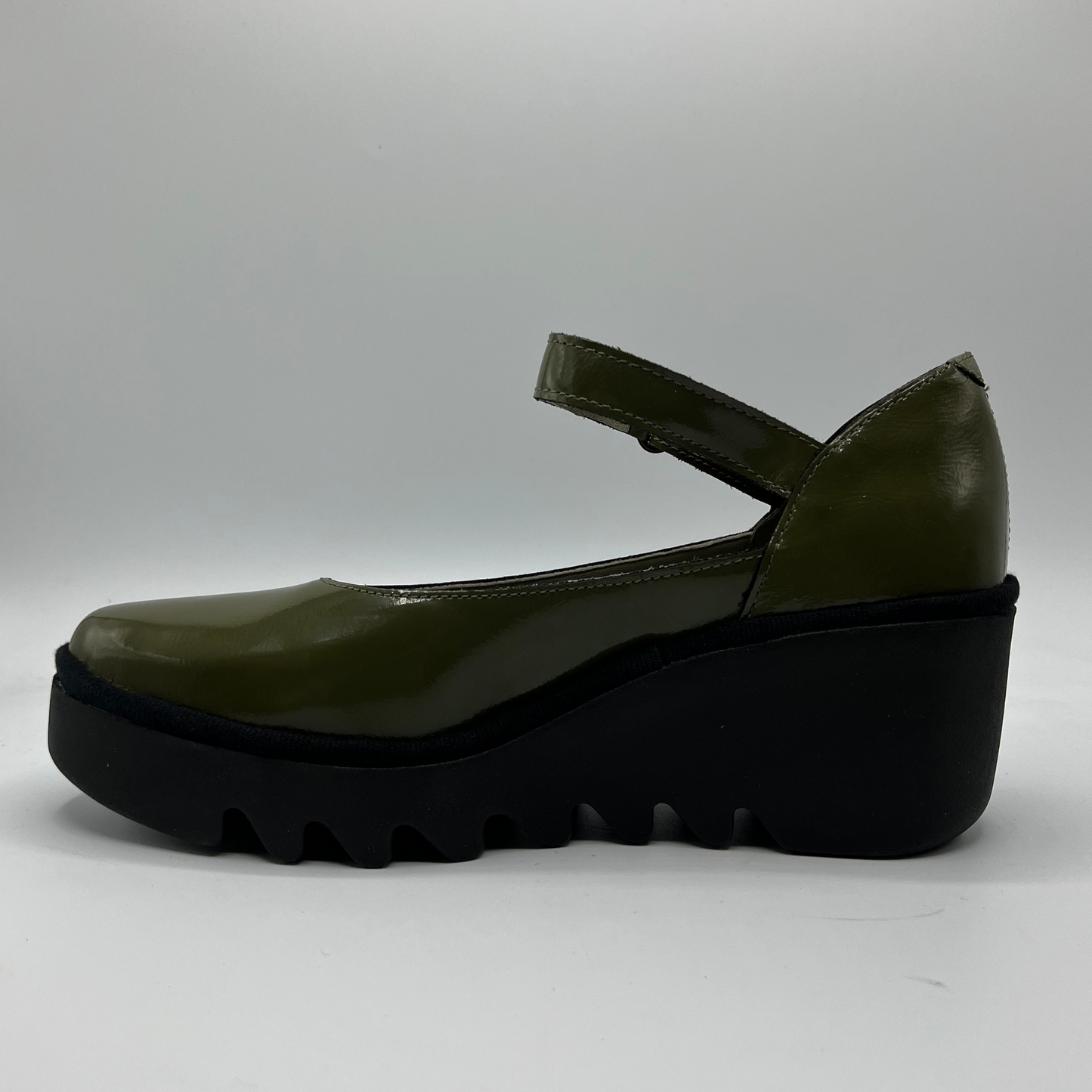 Green shoe with a thick black sole on a gray background