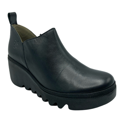 45 degree angled view of black leather bootie with black rubber wedge heel