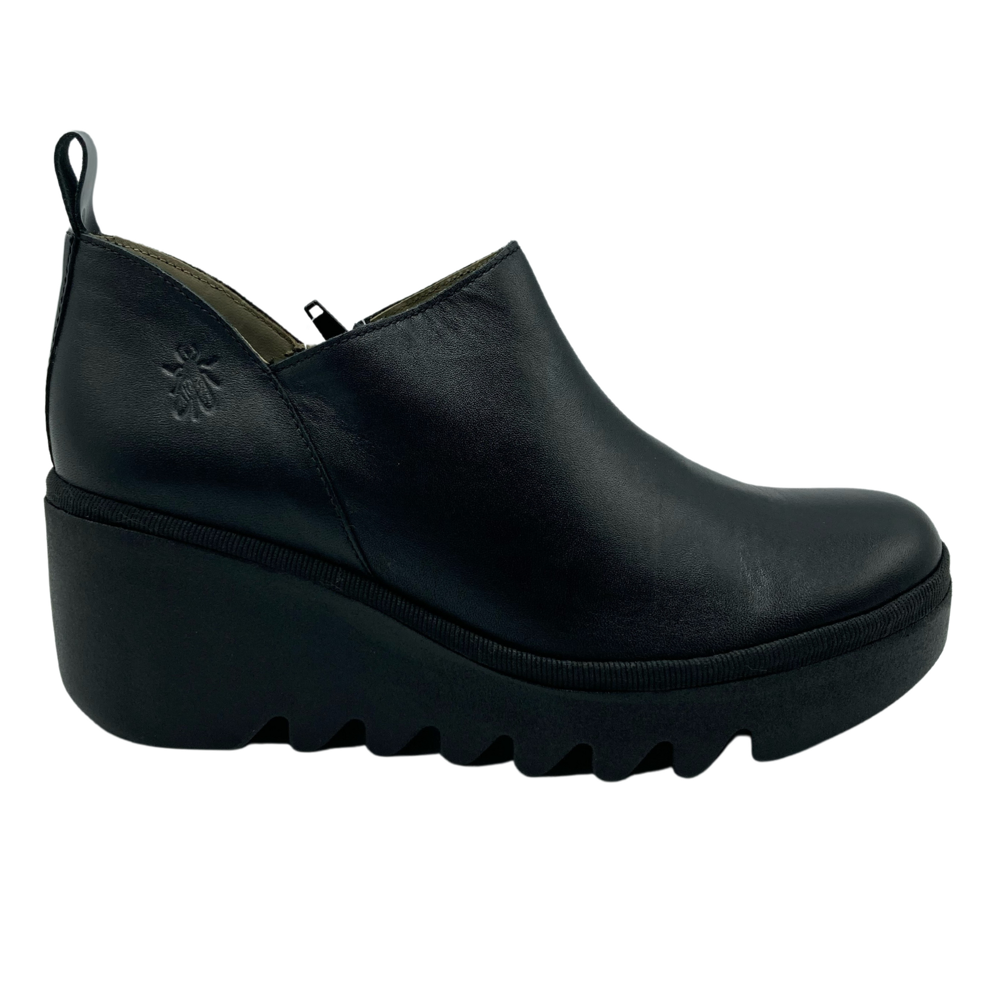 Right facing view of black leather bootie with heel pull tab. Black rubber wedge heel