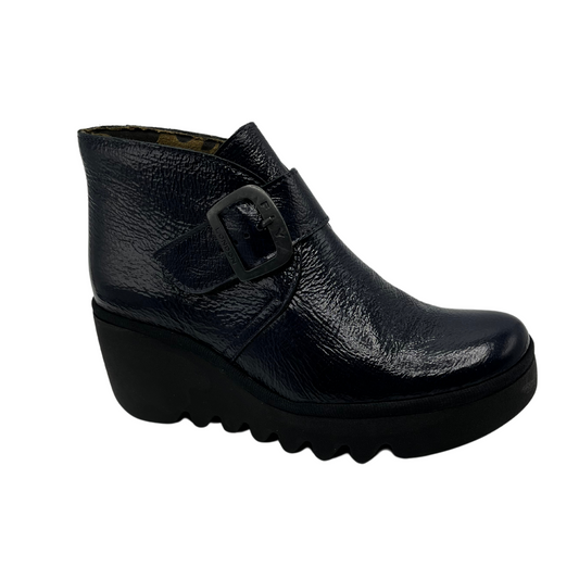 45 degree angled view navy patent leather wedge ankle boot with buckle strap and black outsole