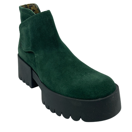 45 degree angled view of green suede ankle boot with velcro closure and black cleated chunky heel