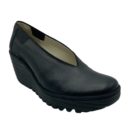 Angled side view of wedge heeled shoe. Black leather upper with elastic panels on each side of ankle
