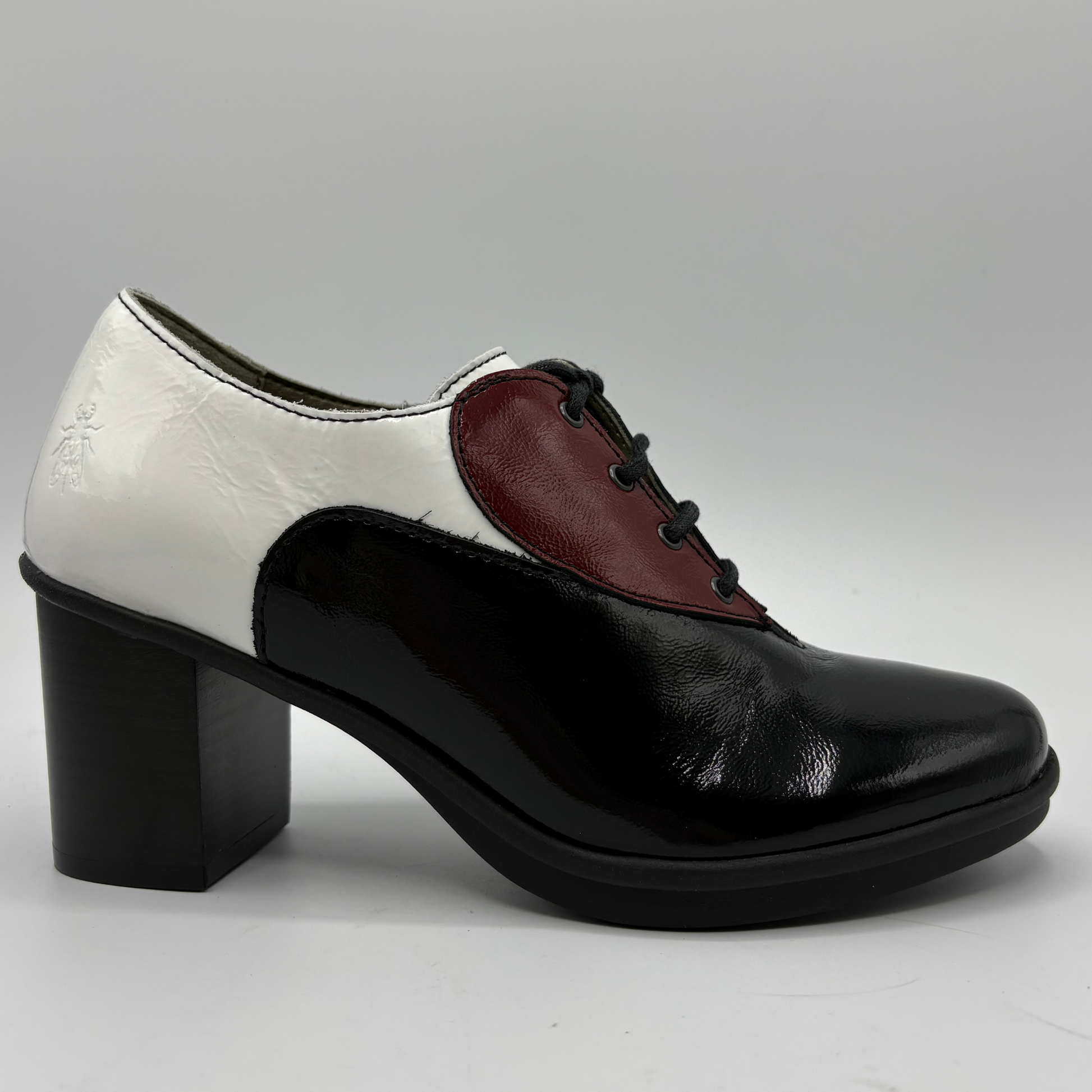 A women's low-heeled oxford-style shoe with a glossy black patent leather toe and quarter, a white leather side panel, and a burgundy leather V-panel on the vamp, finished with black laces and a black block heel.