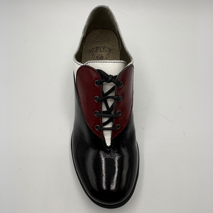 A single women's lace-up shoe photographed from above on a plain light background. The shoe has a glossy black leather toe and heel, a deep burgundy red leather heart-shaped panel across the vamp, and a white leather V-shaped panel behind it.