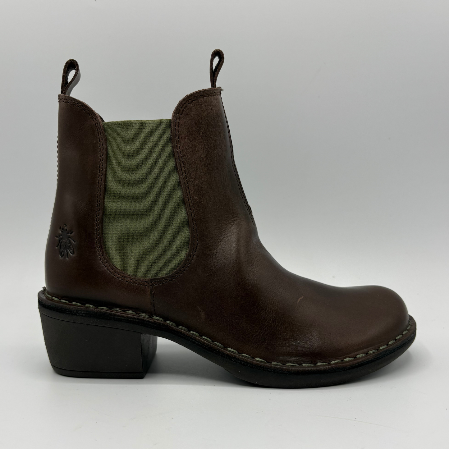 A dark brown leather Chelsea boot with an olive green elastic side panel and a low black block heel, shown from a side profile on a light gray background.