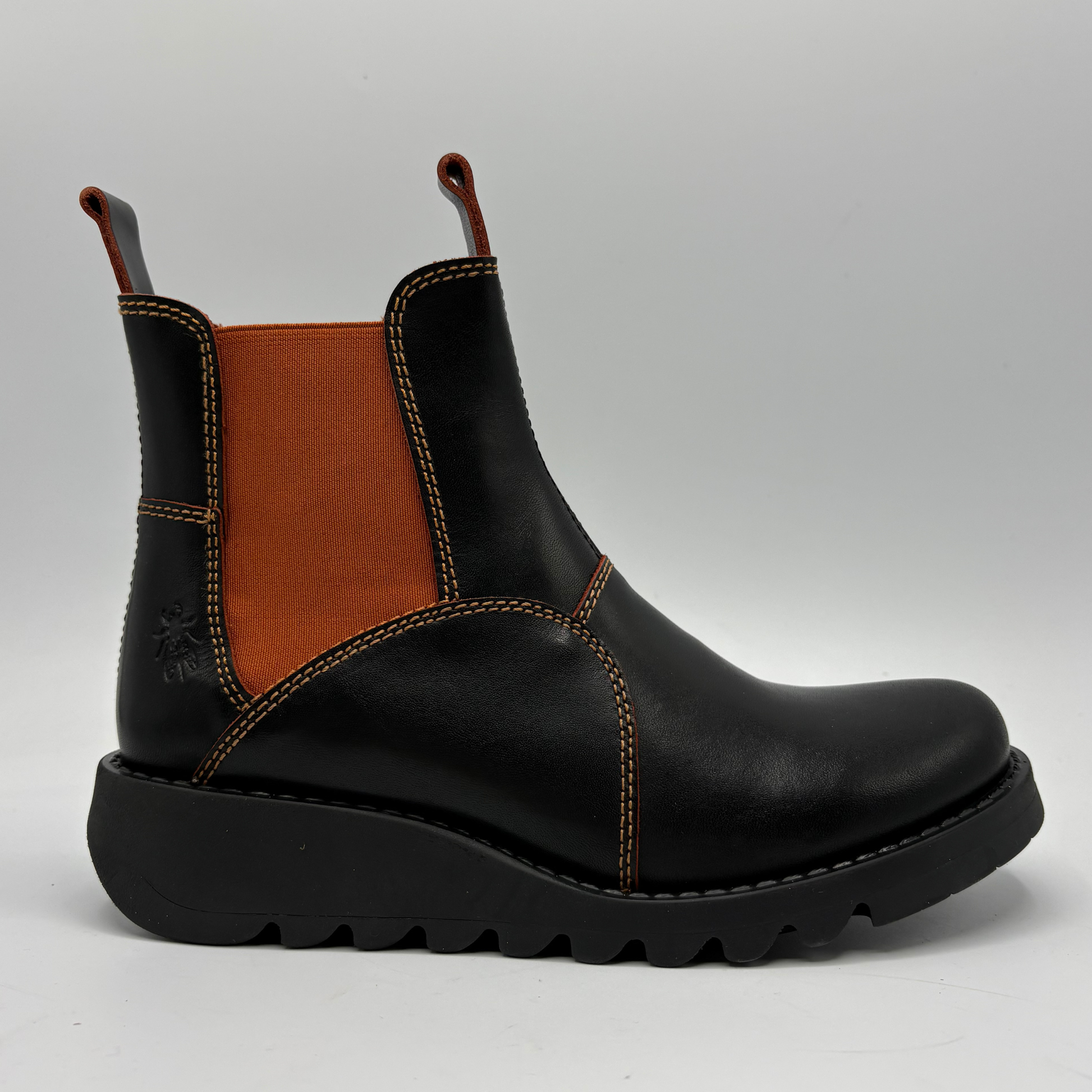 A black leather Chelsea-style ankle boot with a contrasting brown elastic side panel, contrast stitching, and a chunky black lug sole, shown from a side profile on a light gray background.