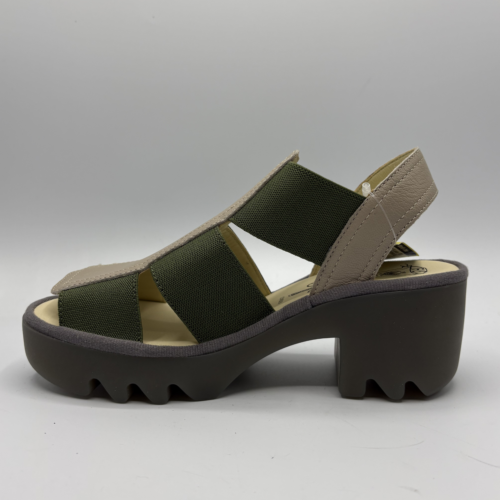 Green sandal with a brown sole on a gray background