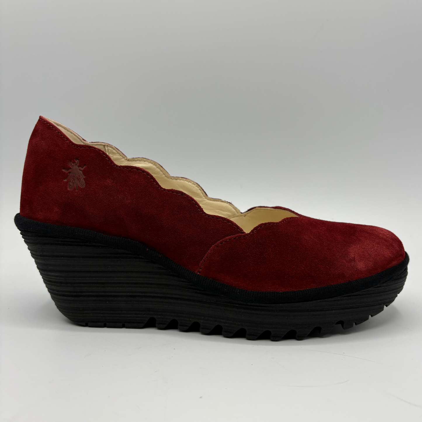 A single burgundy suede wedge shoe with a scalloped edge and a thick black treaded platform sole, shown from a side profile on a light gray background.