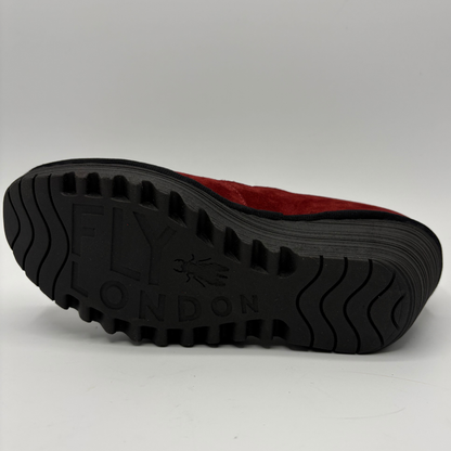 A close-up shot of the black treaded sole of a red shoe, showing the embossed brand name 'FLY LONDON' set against a plain light gray background.