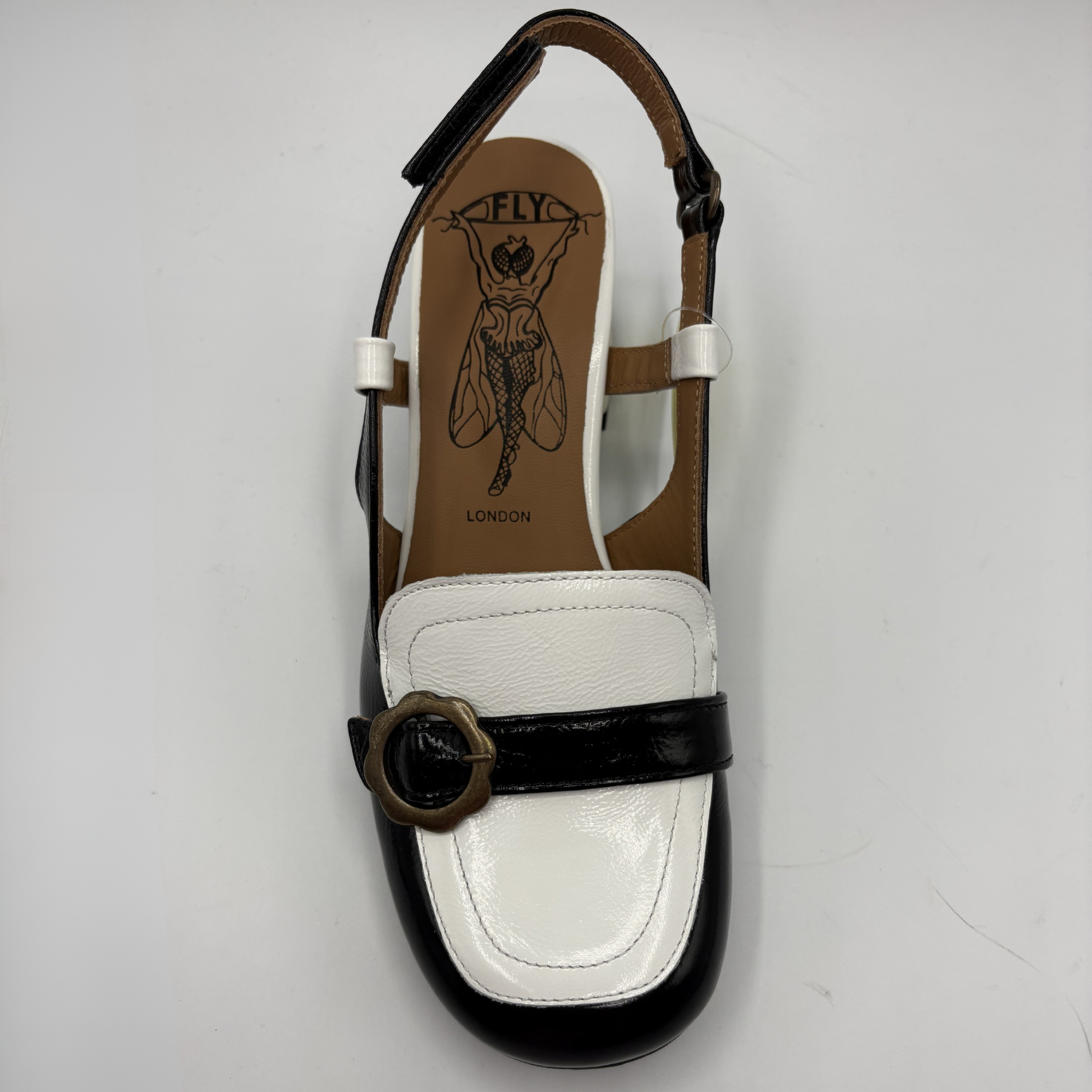 Black and white sandal with a brown insole on a light gray background