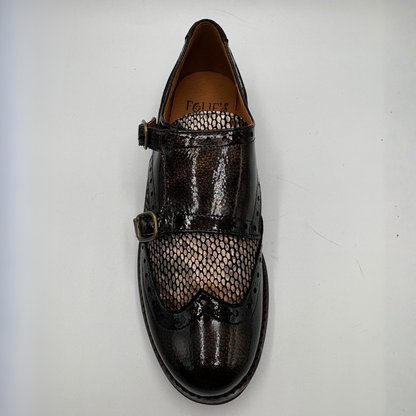 Top view of a shoe with a low heel, leather upper and decorative gold buckles on a white background