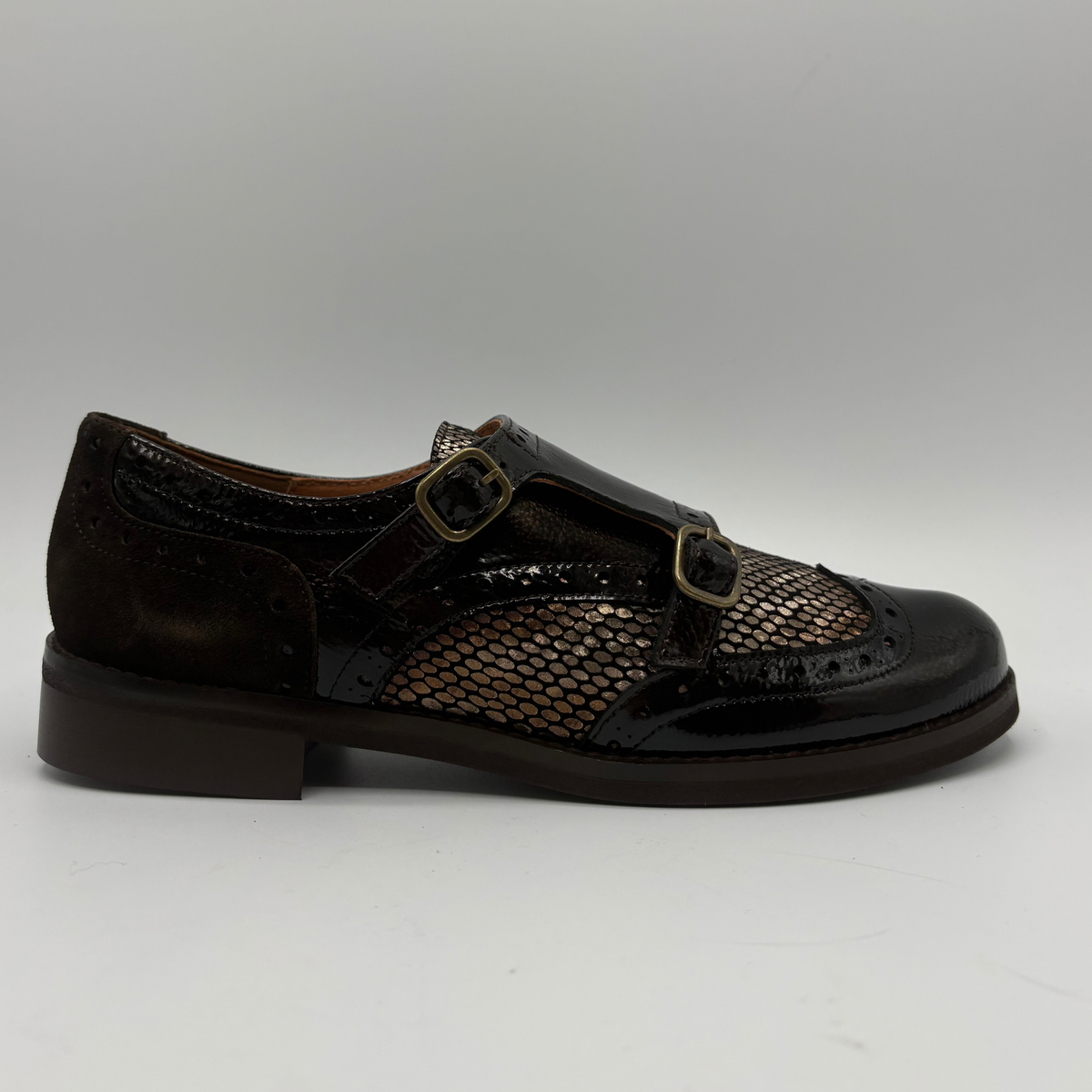 Right facing view of a shoe with a low heel, leather upper and decorative gold buckles on a white background