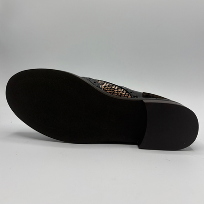 Bottom view of a shoe with a low heel, leather upper and decorative gold buckles on a white background