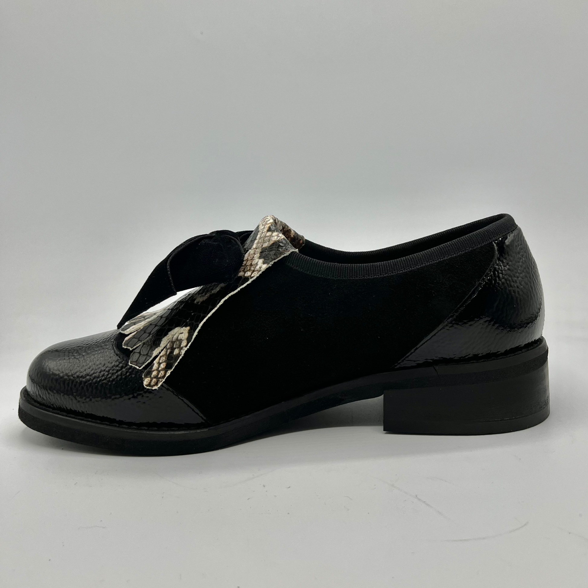 Black shoe with a metallic strap on a gray background